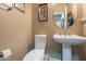 Neat powder room with pedestal sink, toilet, and framed artwork at 336 N Monterey Ct, Casa Grande, AZ 85194