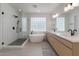 Bright bathroom featuring a glass shower, soaking tub under a glass block window, and a dual sink vanity with modern fixtures at 3707 N 188Th Ave, Litchfield Park, AZ 85340