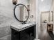 Chic powder room showcasing marble walls, dark vanity, round mirror, and pendant lighting at 4109 N 57Th St, Phoenix, AZ 85018