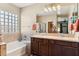 Bathroom with a large mirror, dual sinks, soaking tub, glass block window, and tiled shower at 4960 S Huachuca Pl, Chandler, AZ 85249