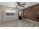 Bright living room features a modern ceiling fan, wood-look vinyl floors and a stylish wood accent wall at 7906 W Catalina Dr, Phoenix, AZ 85033