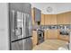 Modern kitchen with stainless steel refrigerator, wooden cabinets, dark range hood and backsplash at 8245 E Bell Rd # 201, Scottsdale, AZ 85260