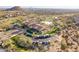 Aerial view of the clubhouse, pool, putting green, and tennis courts with mountain views in the distance at 8525 E Lynwood St, Mesa, AZ 85207