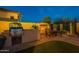 Beautiful backyard with a outdoor kitchen, fireplace, patio and desert landscaping at dusk at 8525 E Lynwood St, Mesa, AZ 85207