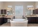 Elegant bathroom featuring a soaking tub, glass block window, dual vanities, and neutral tile at 8525 E Lynwood St, Mesa, AZ 85207