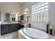 Elegant bathroom featuring a soaking tub, glass block window, dual vanities, and neutral tile at 8525 E Lynwood St, Mesa, AZ 85207