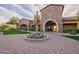 Inviting clubhouse entrance with desert landscaping, a large stone archway, and lush green lawns at 8525 E Lynwood St, Mesa, AZ 85207