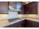 Close-up of the cooktop with stainless steel range hood and custom dark wood cabinetry at 8525 E Lynwood St, Mesa, AZ 85207