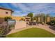 Outdoor kitchen and dining area with a built-in grill, stone fireplace, and manicured lawn at 8525 E Lynwood St, Mesa, AZ 85207