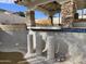 Image of an empty pool area with rock support columns beneath a covered patio and blue tile accents at 9043 E Posada Ave, Mesa, AZ 85212