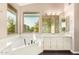 Bright bathroom featuring a soaking tub, white vanity, and a large window providing natural light and lovely views at 9812 E Karen Dr, Scottsdale, AZ 85260