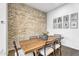 Charming dining room with a wooden table, brick wall, and decorative picture frames at 10719 E Simone Ave, Mesa, AZ 85212