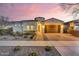Charming single-story home featuring desert landscaping, a two-car garage and a barrel-tile roof at dusk at 10719 E Simone Ave, Mesa, AZ 85212