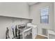 Laundry room featuring modern washer and dryer, overhead shelving, and window for natural light at 10719 E Simone Ave, Mesa, AZ 85212