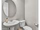 Powder room with stylish pedestal sink, round mirror, and toilet with a convenient hand soap dispenser at 10719 E Simone Ave, Mesa, AZ 85212