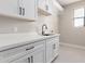 Laundry room features sleek white cabinets, black hardware, and a modern faucet at 13012 S 218Th Ave, Buckeye, AZ 85326