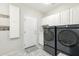 Modern laundry room with front-load washer and dryer, white cabinets, and decorative floor tiles at 1321 W Shellfish Dr, Gilbert, AZ 85233