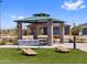 A gazebo, bench and two cornhole platforms are in a community park with an artificial lawn for residents to enjoy at 17683 W Odeum Ln, Goodyear, AZ 85338