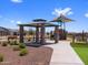 Community park featuring picnic tables under gazebo and a covered playground, with nearby benches for parents' relaxation at 17683 W Odeum Ln, Goodyear, AZ 85338