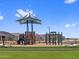 Well-maintained community playground features turf, covered play structures and open play spaces under a clear blue sky at 17683 W Odeum Ln, Goodyear, AZ 85338