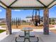 A picnic table under a gazebo overlooking a playground and park area at 17683 W Odeum Ln, Goodyear, AZ 85338