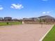 A community sand volleyball court is surrounded by lush green grass and landscaping with homes nearby at 17683 W Odeum Ln, Goodyear, AZ 85338