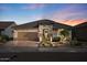 Beautiful home with landscaped front yard, brick driveway, and warm exterior lighting at sunset at 18961 N 259Th Ave, Buckeye, AZ 85396