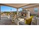 Covered outdoor living space with a stone fireplace and comfortable seating arrangement at 18961 N 259Th Ave, Buckeye, AZ 85396