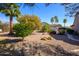 Well-kept backyard with desert landscaping, trees, and a glimpse of the home's exterior at 19824 N Valencia Ct, Surprise, AZ 85374