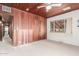 A spacious bedroom with wood paneling, neutral carpet, and natural light from a window at 2107 N Campo Allegre Dr, Tempe, AZ 85288