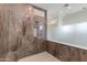 Walk-in shower tiled in marbled stone with frameless glass and mosaic-tiled floor at 24548 N 121St Pl, Scottsdale, AZ 85255