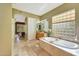 Serene bathroom featuring a large soaking tub, travertine tile, and bright, natural light at 3531 E Norwood Cir, Mesa, AZ 85213