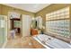 Bright bathroom featuring a large soaking tub with travertine tile, and granite counters at 3531 E Norwood Cir, Mesa, AZ 85213