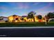 Inviting single-story home with lush landscaping, enhanced by warm exterior lighting at dusk at 3531 E Norwood Cir, Mesa, AZ 85213