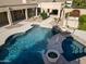 A luxurious pool with a spa and a waterfall feature, complemented by lush landscaping and a covered patio at 3531 E Norwood Cir, Mesa, AZ 85213