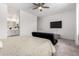 Spacious bedroom with carpet, a view to the bathroom, a mounted TV, and a ceiling fan at 36284 W San Clemente Ave, Maricopa, AZ 85138