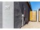 Exterior detail of a home displaying the house number with gray stucco walls and a wooden side gate at 36284 W San Clemente Ave, Maricopa, AZ 85138