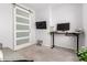 Functional home office space with a sliding door, mounted TV, and a sit-stand desk at 36284 W San Clemente Ave, Maricopa, AZ 85138