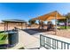 Shaded playground with slides and climbing area, adjacent to picnic tables and a grassy area at 36284 W San Clemente Ave, Maricopa, AZ 85138