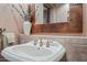 Stylish powder room featuring a unique copper-framed mirror and elegant white vessel sink at 36601 N Mule Train Rd # 40A, Carefree, AZ 85377