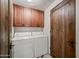 Functional laundry room with white washer and dryer and wooden cabinets for storage at 36601 N Mule Train Rd # 40A, Carefree, AZ 85377