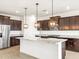 Island kitchen with dark wood cabinetry, stainless steel appliances, and quartz countertops at 37342 W San Clemente St, Maricopa, AZ 85138