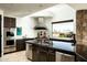 Modern kitchen with stainless steel appliances, dark cabinets and a large island with breakfast bar seating at 41688 N 111Th Pl, Scottsdale, AZ 85262