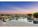 Desert backyard featuring a lagoon-style pool and spa amidst lush landscaping and scenic sunset backdrop at 41688 N 111Th Pl, Scottsdale, AZ 85262