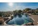 Beautiful backyard oasis with a rock-accented pool, lush desert landscaping, and relaxing lounge area at 41688 N 111Th Pl, Scottsdale, AZ 85262