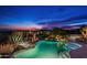 Backyard featuring a lagoon-style pool and spa with lush desert landscaping and nighttime city views at 41688 N 111Th Pl, Scottsdale, AZ 85262