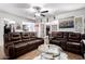 Open-concept living room with a stone accent wall, plush leather seating, and seamless flow to the dining area at 4630 W El Caminito Dr, Glendale, AZ 85302