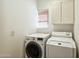 Laundry room features modern washer and dryer, storage cabinet and window at 5310 W Melinda Ln, Glendale, AZ 85308