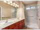 Bright bathroom featuring a double sink vanity, a large mirror, and a shower with grab bars at 6129 S White Pl, Chandler, AZ 85249