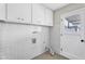 Bright laundry room featuring white cabinets, tiled walls, and utility connections for modern convenience at 7745 N 33Rd Ave, Phoenix, AZ 85051